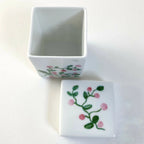 Boîte à bijoux en porcelaine blanche, couvercle ouvert, motif floral rose.