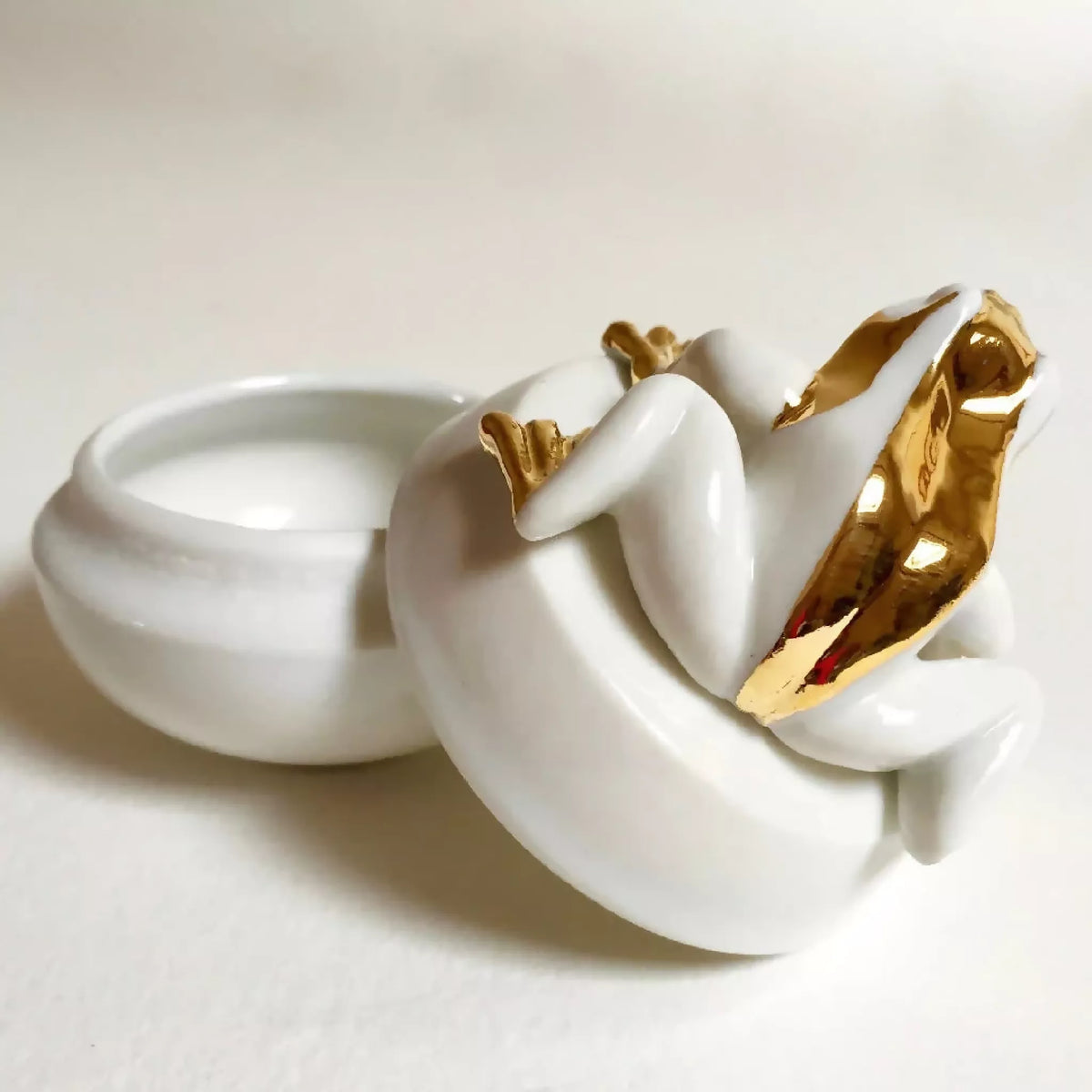 Boîte à bijoux grenouille blanche avec ouverture du dessus, finitions dorées sur le corps.
