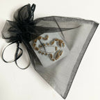 Boîte à bijoux en porcelaine dans un pochon en organza noir, motif scorpion doré.
