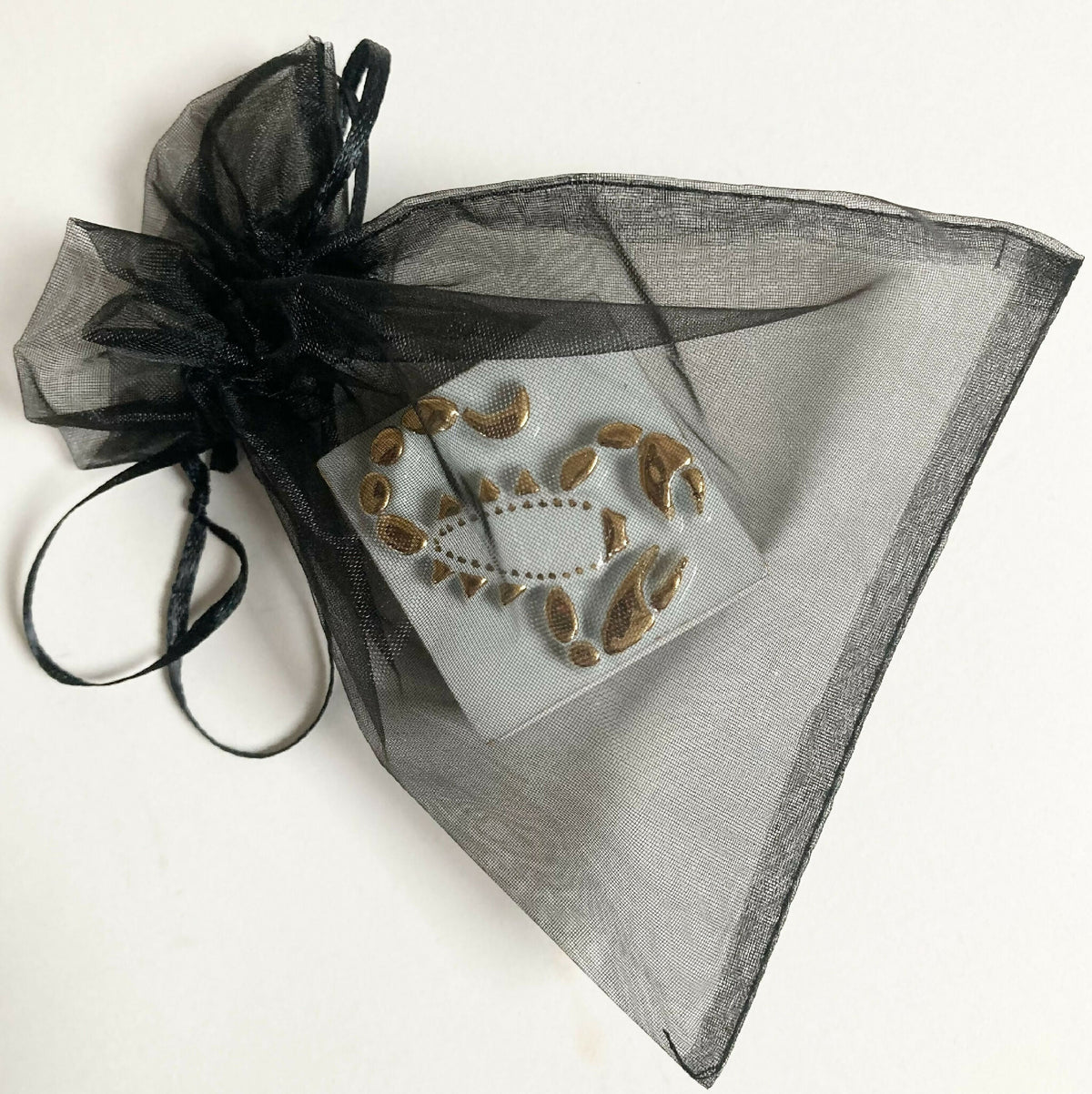 Boîte à bijoux en porcelaine dans un pochon en organza noir, motif scorpion doré.