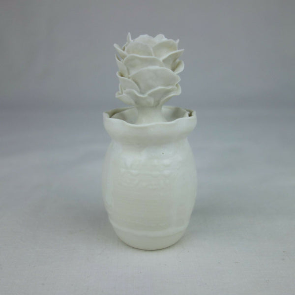 Vase en céramique blanc, forme cylindrique avec fleurs en relief sur le dessus.