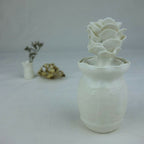 Vase en céramique blanc avec fleurs en relief empilées au centre, vue de profil.