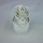 Vase en céramique blanc, fleurs en relief empilées, vue inclinée rapprochée.