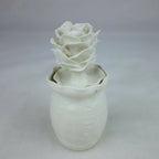 Vase en céramique blanc, silhouette cylindrique et décoration florale en relief.
