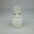 Vase en céramique blanc, fleurs en relief au sommet, vue entière centrée.