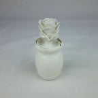 Vase en céramique blanc avec décoration florale en relief, vue de face légère.