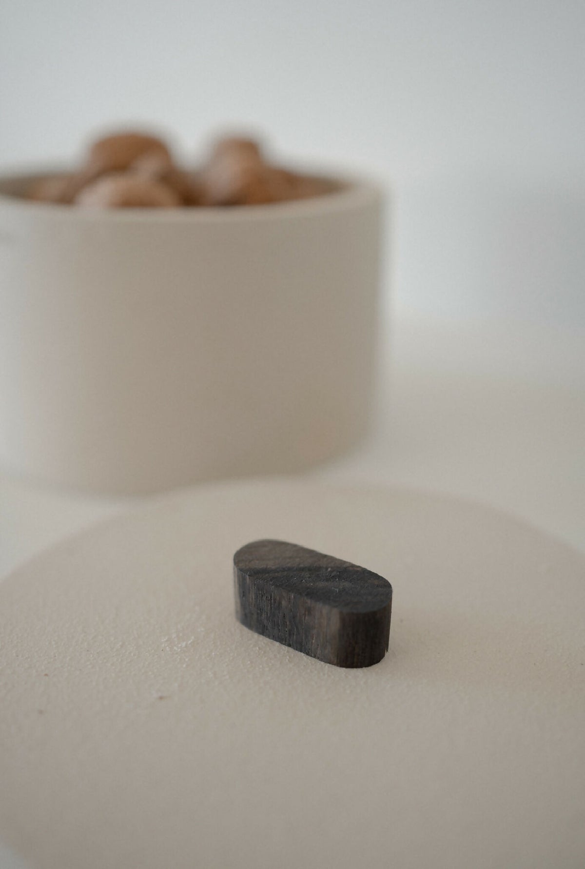 Boîte cylindrique beige TERA avec couvercle noir posé à côté