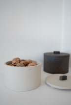 Boîte cylindrique TERA STONE blanche ouverte avec fruits secs, couvercle pierre sombre