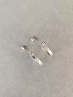 Paire de boucles d’oreilles courbes argentées, texture granuleuse sur la tige