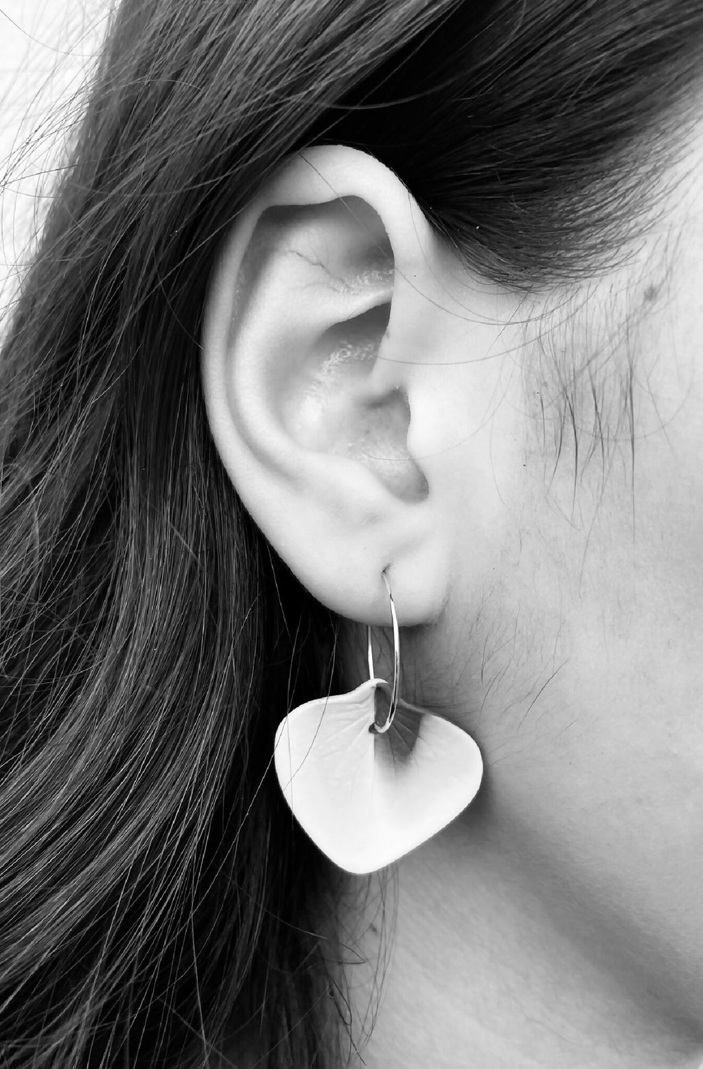 Boucles d’oreille créoles en porcelaine, forme de pétales, portées en vue de profil.