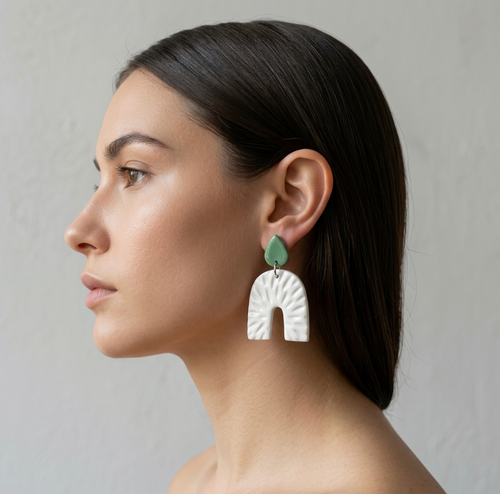 Boucles d’oreille arc en porcelaine blanche en relief, goutte vert menthe, portées.