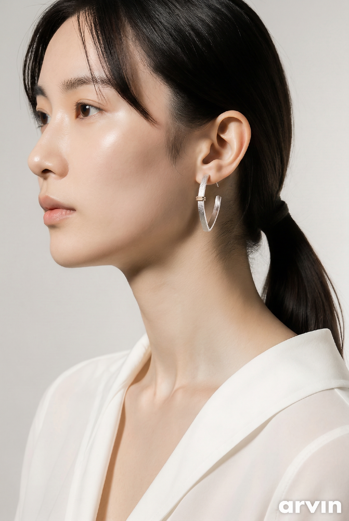 Boucles d’oreilles courbes avec anneau bicolore argenté et doré, portées à l’oreille