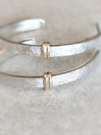 Détails des boucles d’oreilles courbes argentées : fermoirs dorés et surface texturée