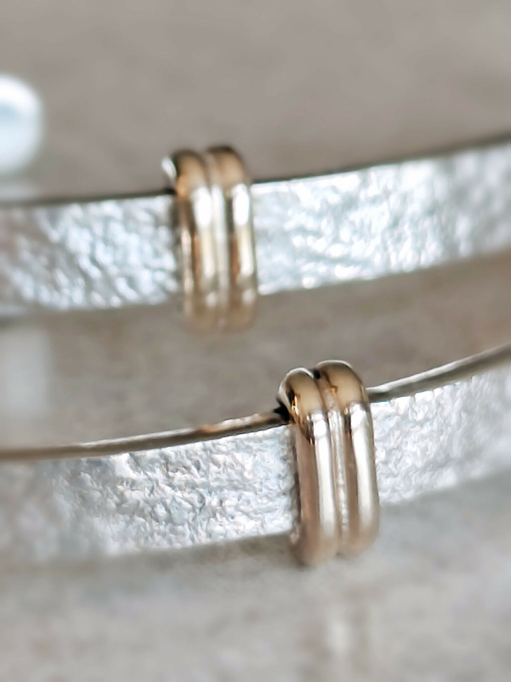 Gros plan sur les boucles d’oreilles courbes : anneaux dorés et reflets argentés