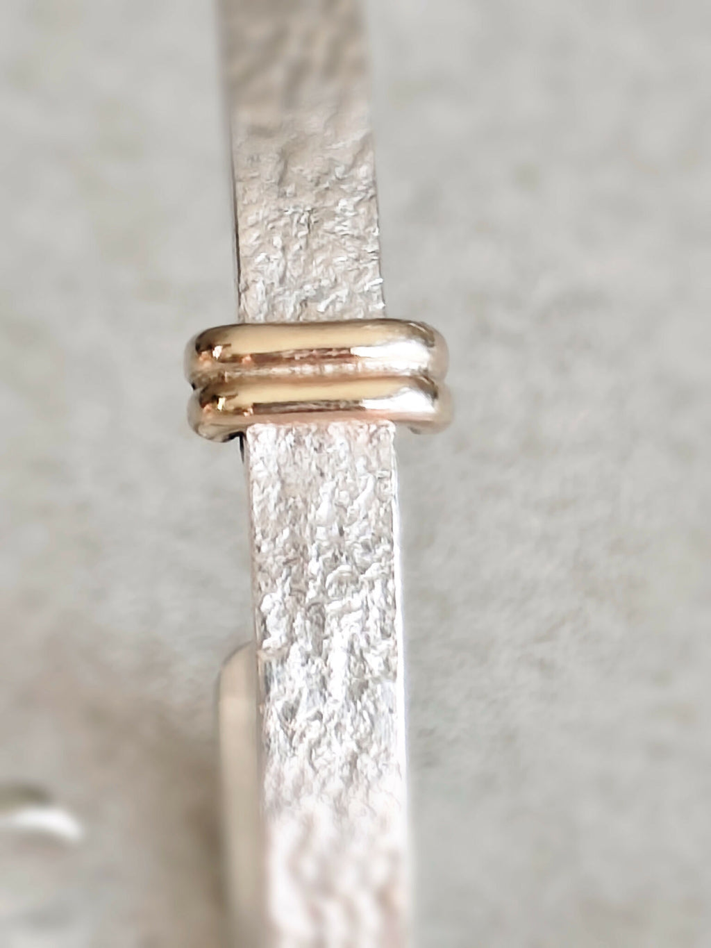 Détail du fermoir des boucles d’oreilles courbes : barre dorée et attache arrondie