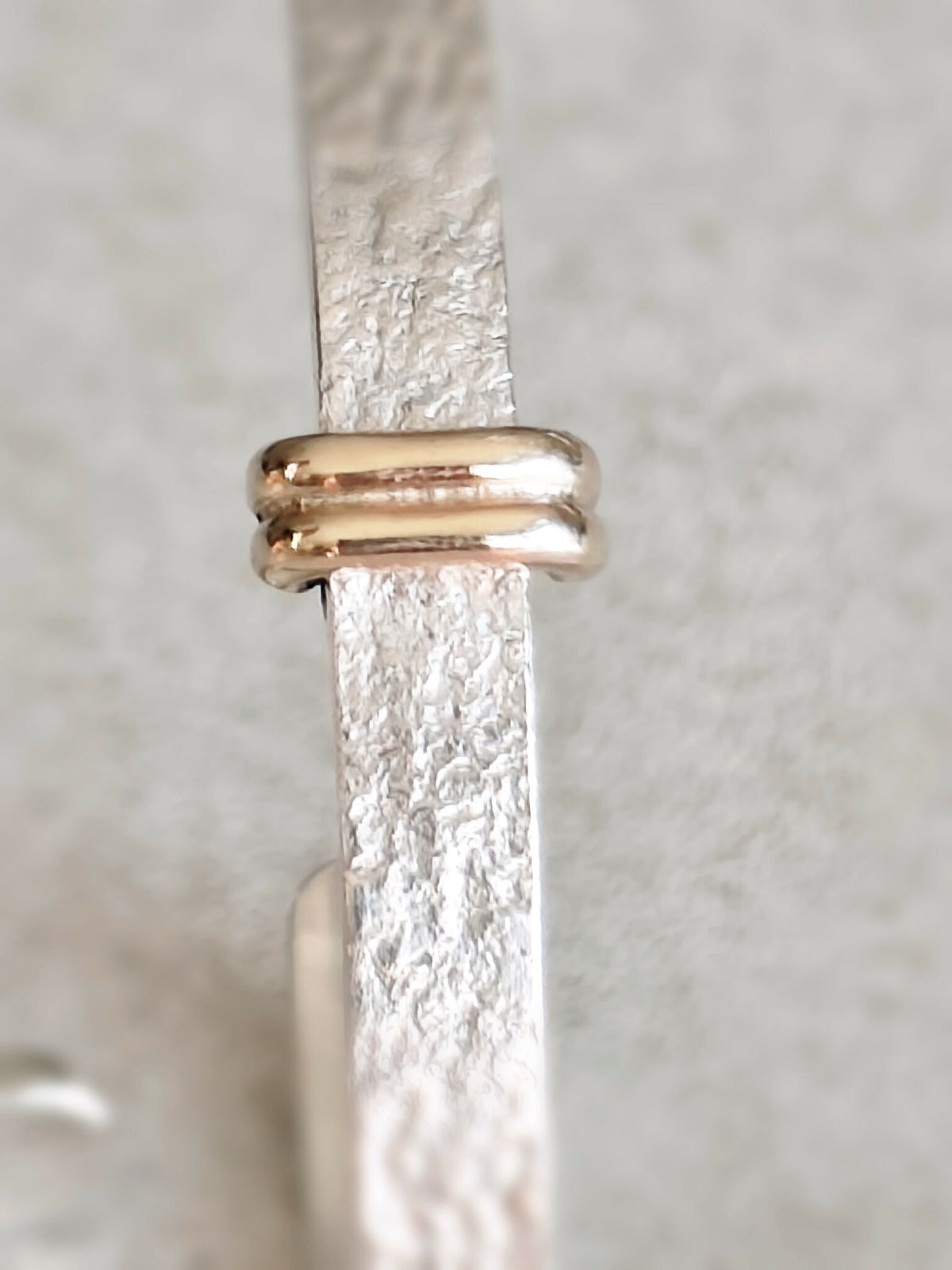 Détail du fermoir des boucles d’oreilles courbes : barre dorée et attache arrondie