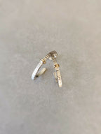 Boucles d’oreilles courbées argentées, rayures fines et accents dorés, vue rapprochée