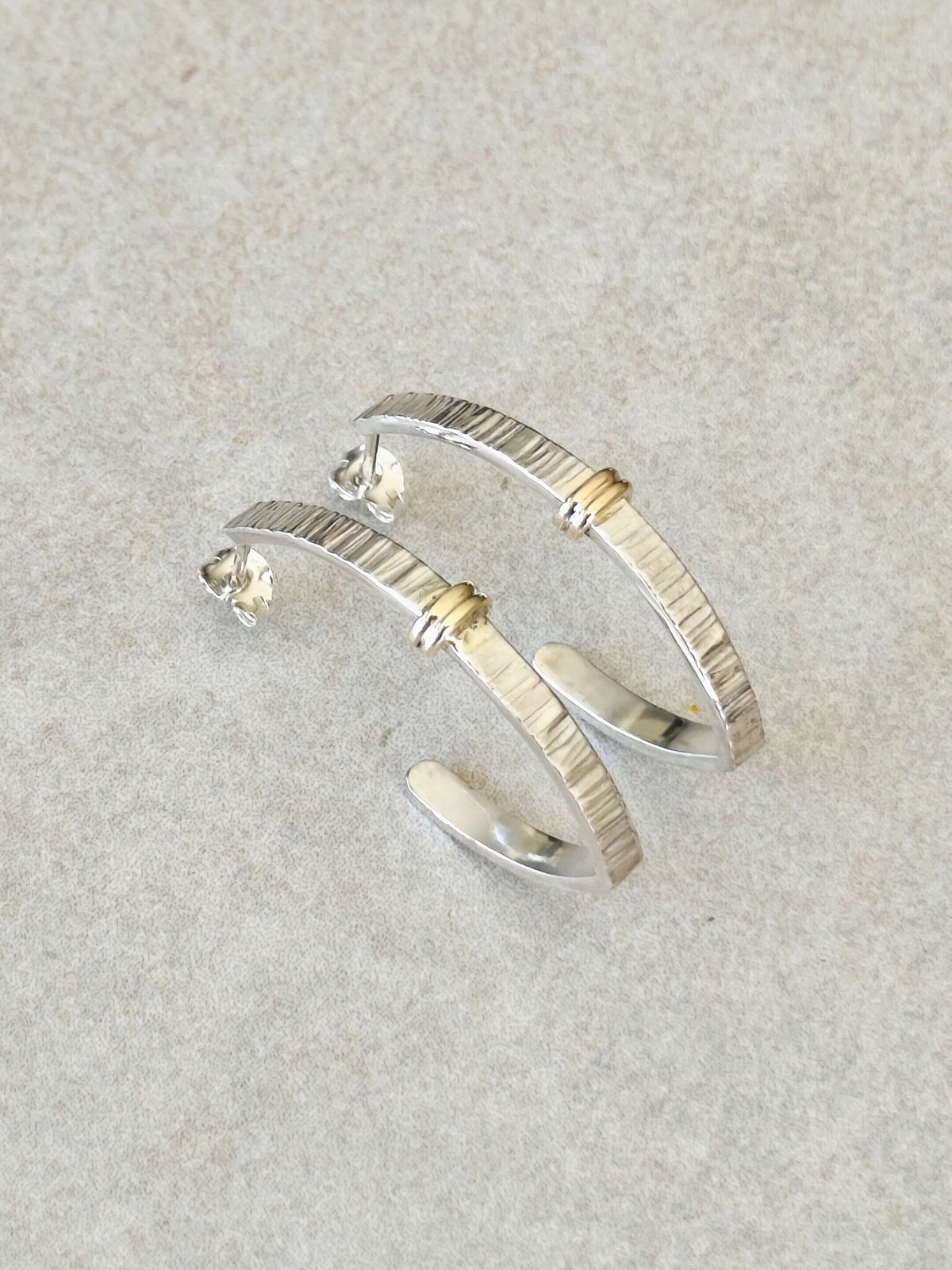 Boucles d’oreilles courbées en métal argenté, rayures verticales et détails dorés