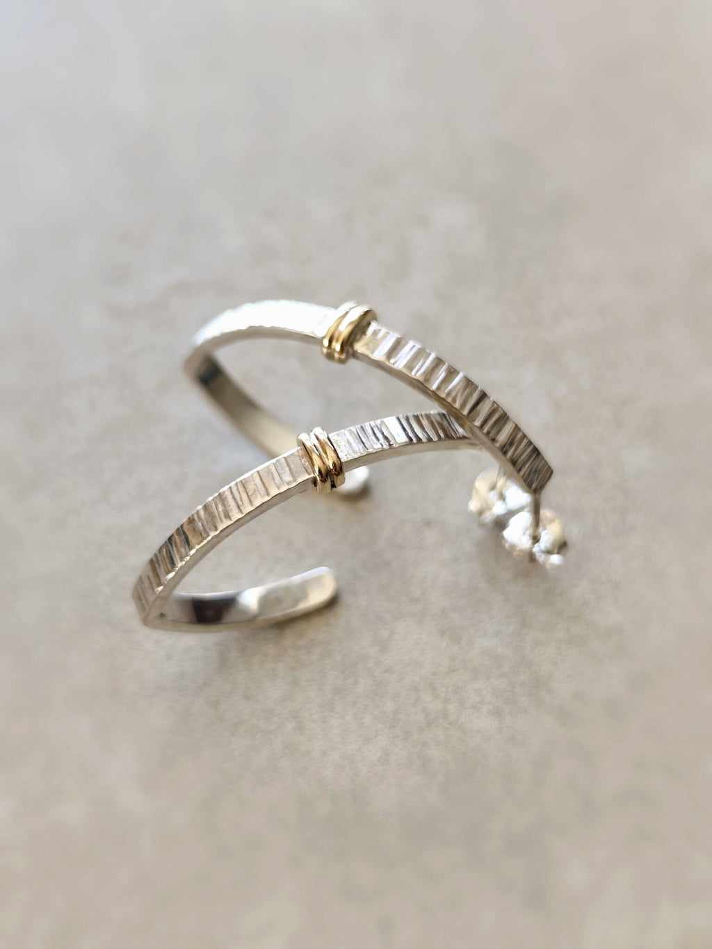 Boucles d’oreilles courbées argentées, inserts dorés, fermoir visible, finition brillante
