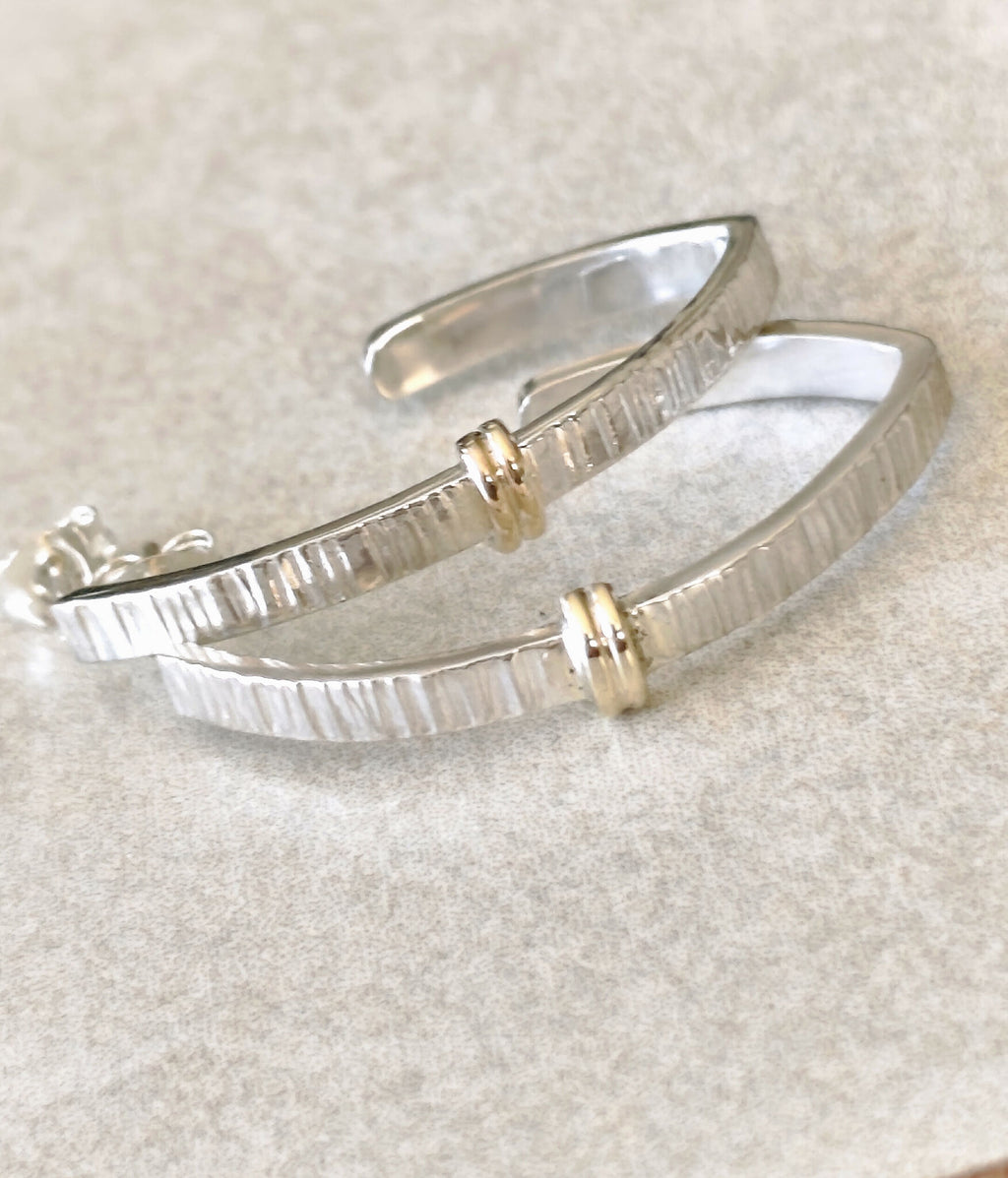 Boucles d’oreilles courbées argentées, inserts dorés au centre, texture striée