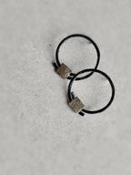 Boucles d’oreilles anneaux noirs, carrés texturés dorés, position croisées