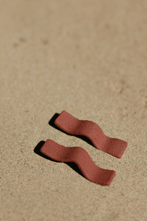 Boucles d’oreilles pendantes en barres courbées rouge brique, vue rapprochée