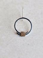Boucles d’oreilles pendantes : anneau noir unique avec carré doré texturé et tige d’accroche.