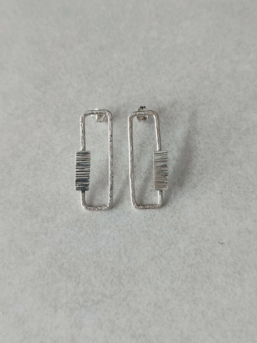 Boucles d’oreilles rectangulaires argentées, rayures verticales sur le centre.