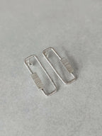 Boucles d’oreilles rectangulaires argentées, angle latéral sur la texture du centre.