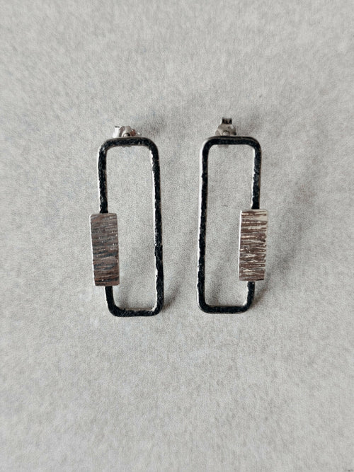 Boucles d’oreilles rectangulaires, plaque striée et bordure foncée, fixation visible