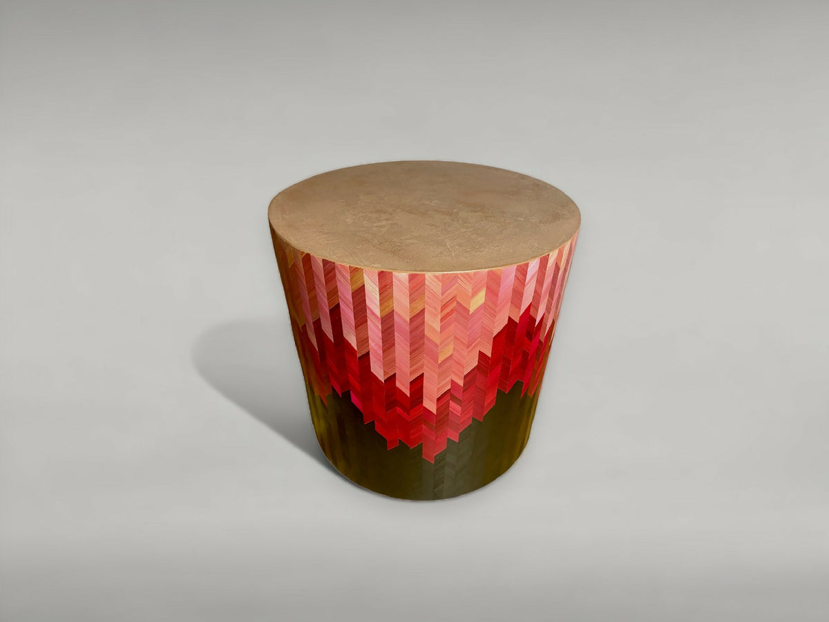 Bout de canapé rond vue en biais : motif chevrons rouge, dessus beige, base sombre.