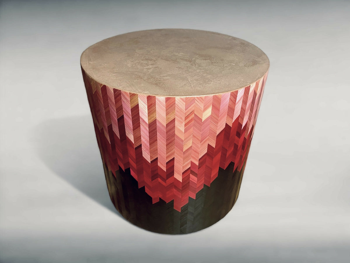 Bout de canapé rond, vue trois-quarts : motif chevrons rouge et beige sur base sombre.