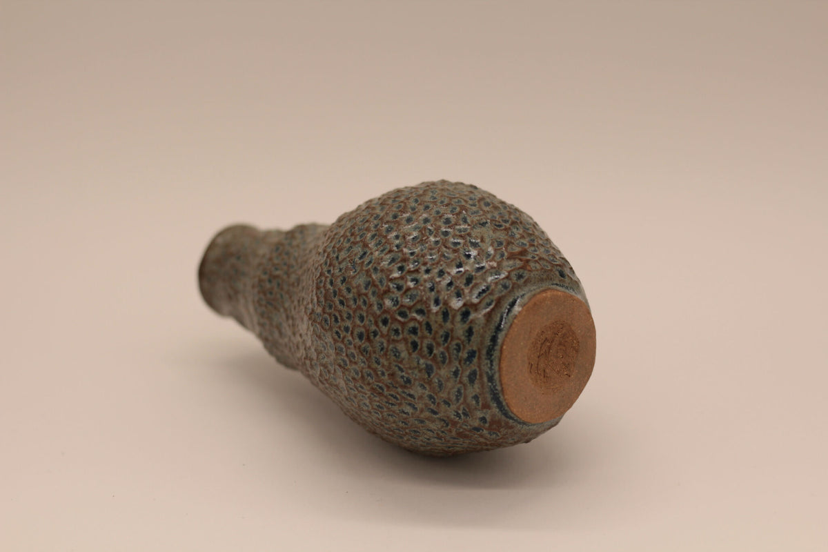 Petite bouteille en céramique bleu-gris, vue latérale avec base arrondie brunâtre
