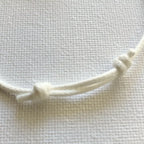 Détail bracelet : cordon blanc torsadé et nœuds en porcelaine blanche