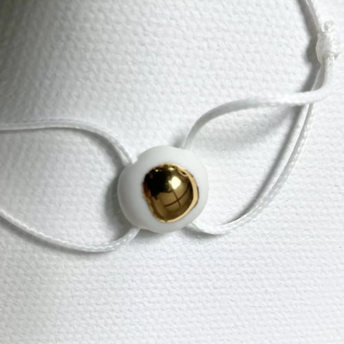 Bracelet goutte d’or : perle ronde dorée sur cordon blanc