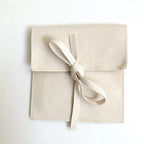 Bracelet en cordon blanc avec perle dorée sur pochette beige