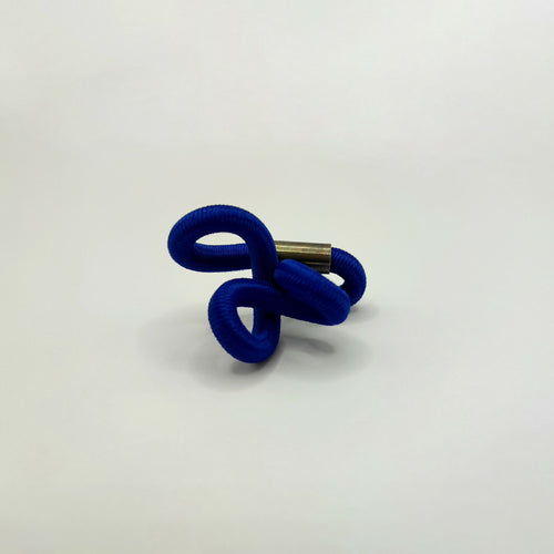 Broche en entrelacs de tissu bleu et tige métallique dorée.