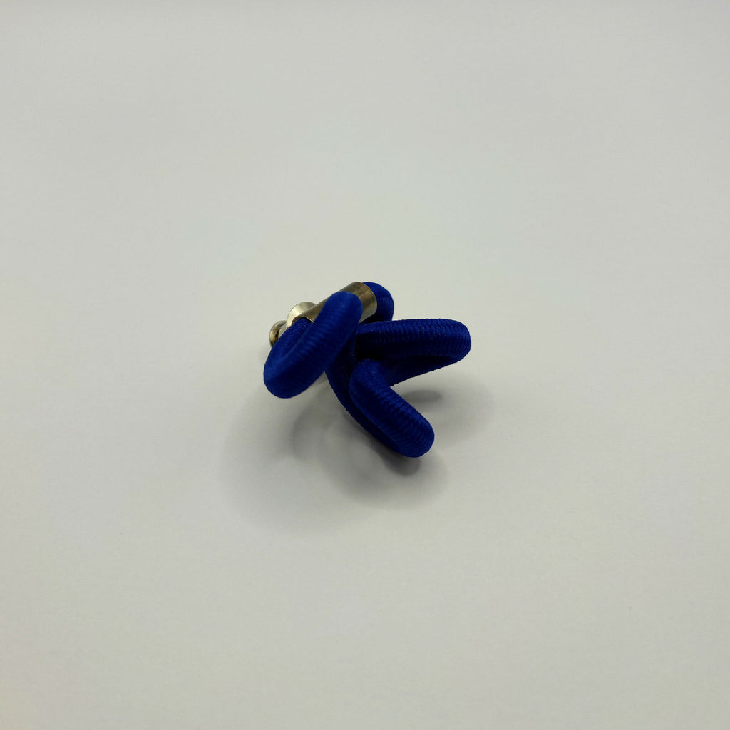 Broche en tissu bleu noué avec fermeture à l’arrière en métal doré.