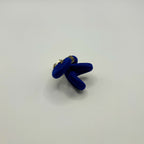 Broche en tissu bleu noué avec fermeture à l’arrière en métal doré.