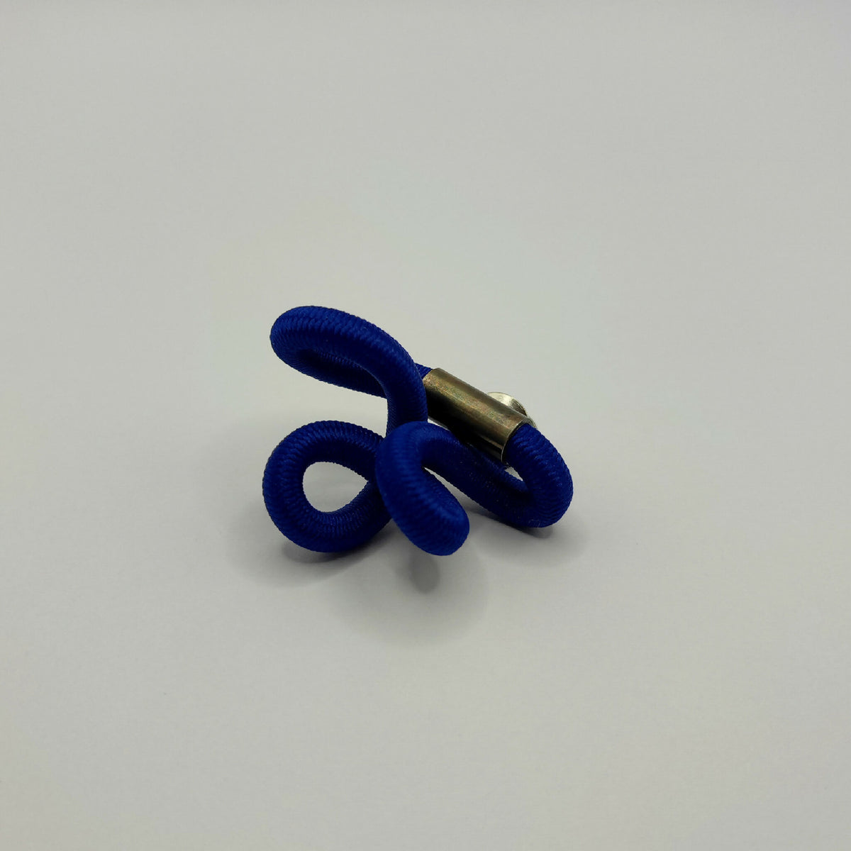 Broche entrelacée bleu avec tige métallique dorée et anneaux texturés.