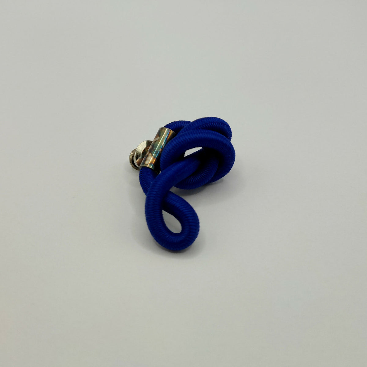 Broche en entrelacs de tissu bleu, attache métallique argentée.