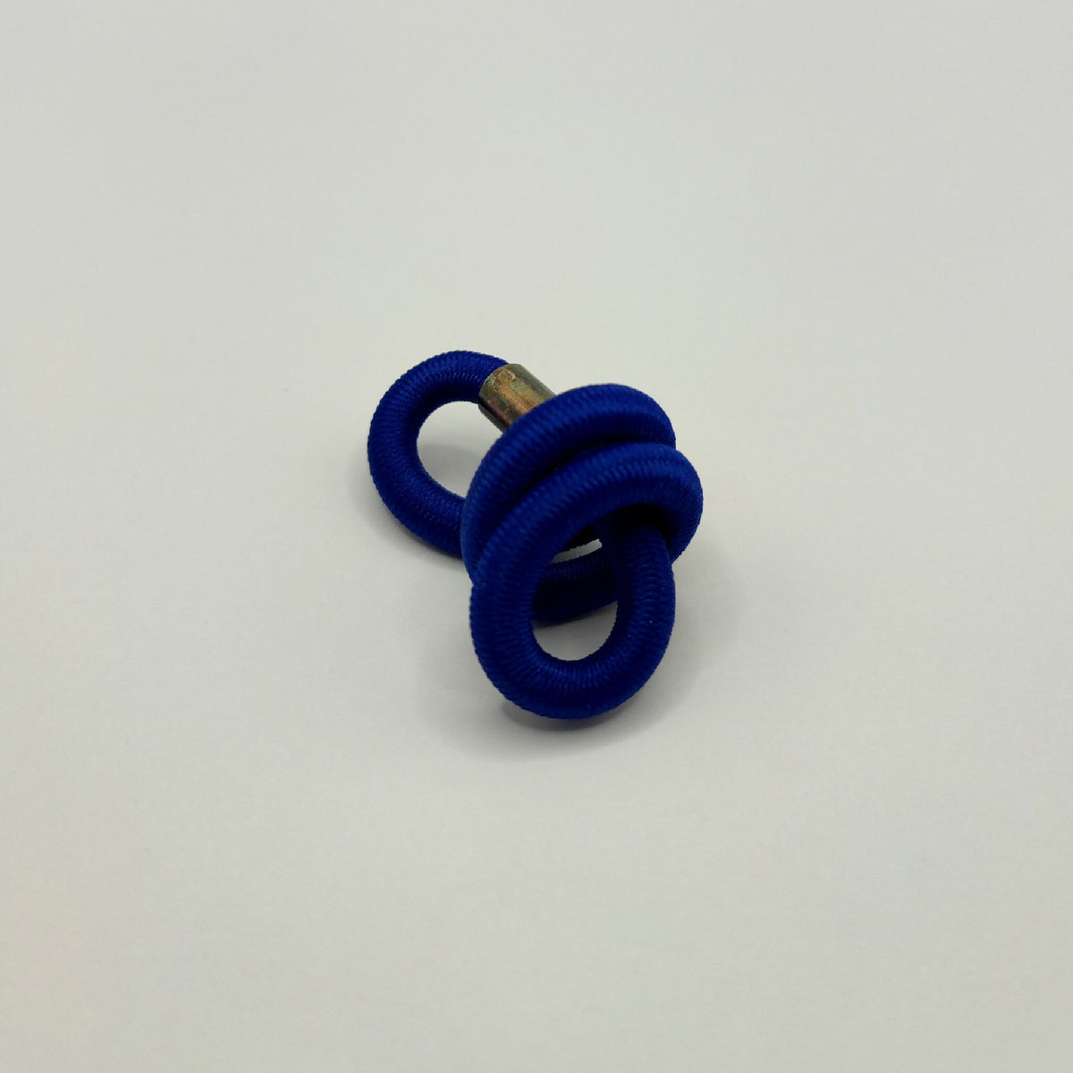 Broche en tissu bleu en forme d’entrelacs, épingle dorée et anneaux.