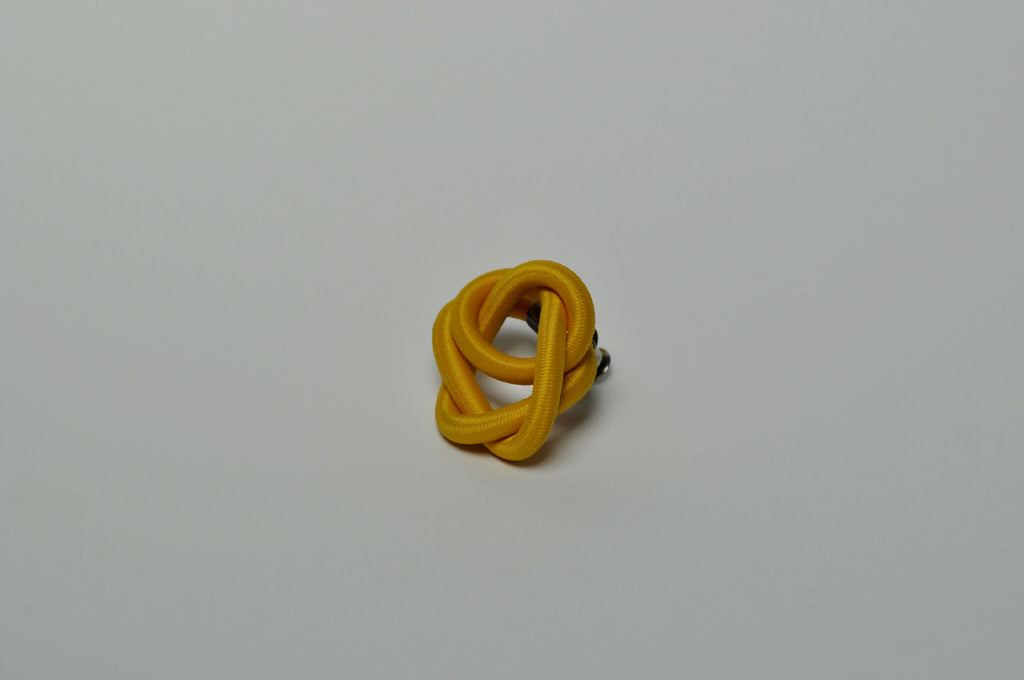 Broche entrelacée jaune vue de trois-quarts, anneaux enchevêtrés.