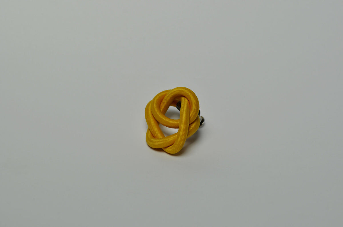 Broche entrelacée jaune vue de trois-quarts, anneaux enchevêtrés.