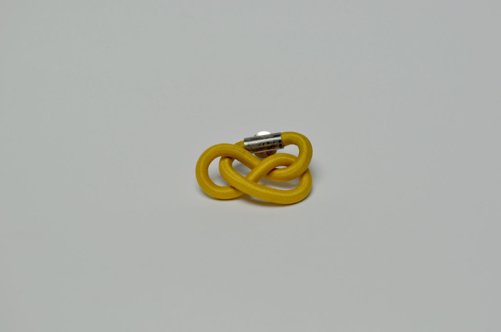 Broche entrelacée jaune avec tige métallique, vue latérale.