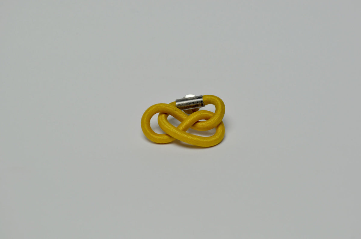 Broche entrelacée jaune avec tige métallique, vue latérale.
