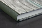 Tranche du cahier et dos cuir vert, couverture gris clair à motifs ondulés.