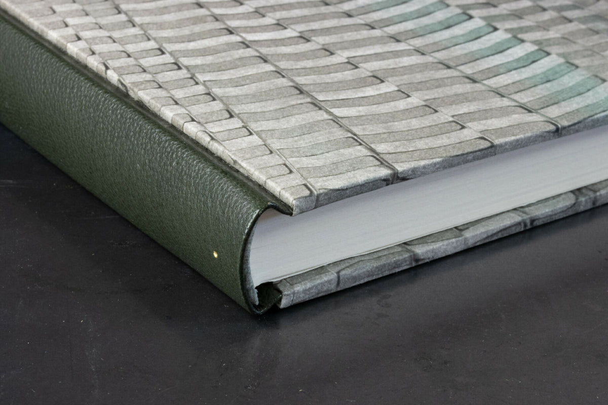 Tranche du cahier et dos cuir vert, couverture gris clair à motifs ondulés.