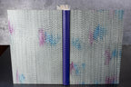 Cahier à couverture cuir gris clair, motifs ondulés, dos bleu et ruban de fermeture.