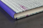 Carnet à dos en cuir violet et tranches crème visibles, couverture motif zigzag.